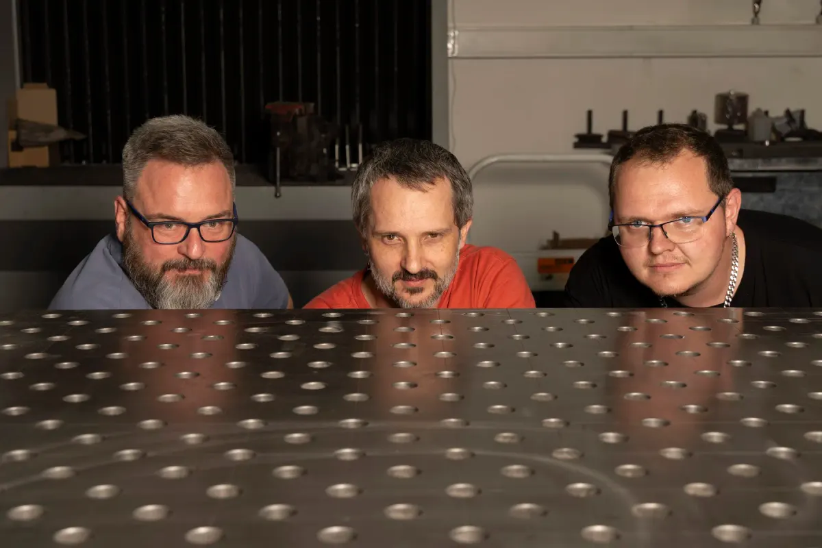 The prototype.builders team behind a perforated welding table in our Prague workshop